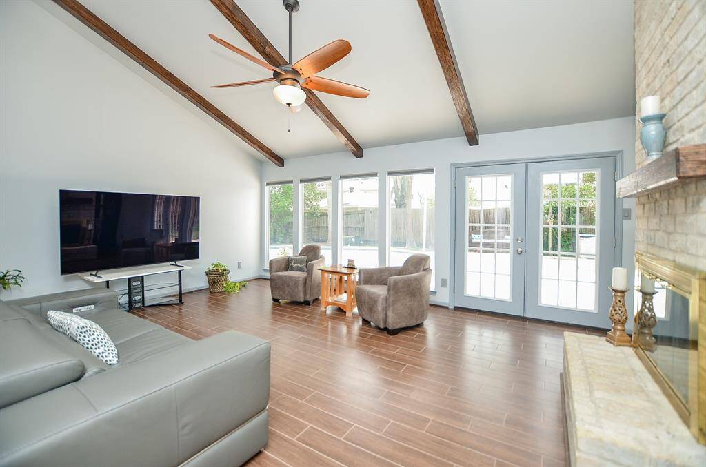 Soaring cathedral ceilings and handsome wood beams add depth in this already generous Living Room.  Gas log fireplace and note the floor to ceiling windows that overlook the sparkling pool.  Pool service included.