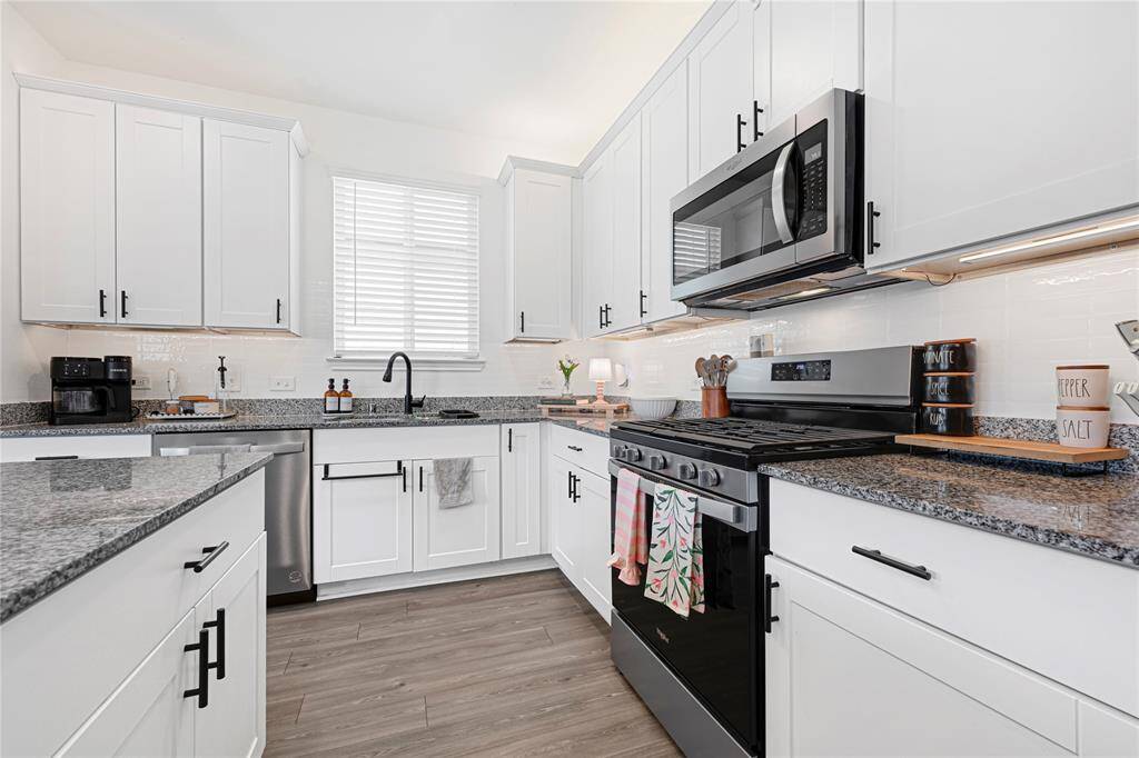 Modern kitchen with granite countertops, stainless steel appliances, ample cabinetry, and oversized island.