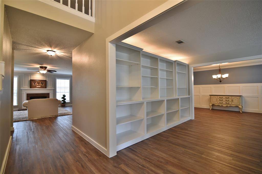 Custom built bookcases line one entire wall in this front living area/office/library.....back lighting above the bookcases is an elegant touch!