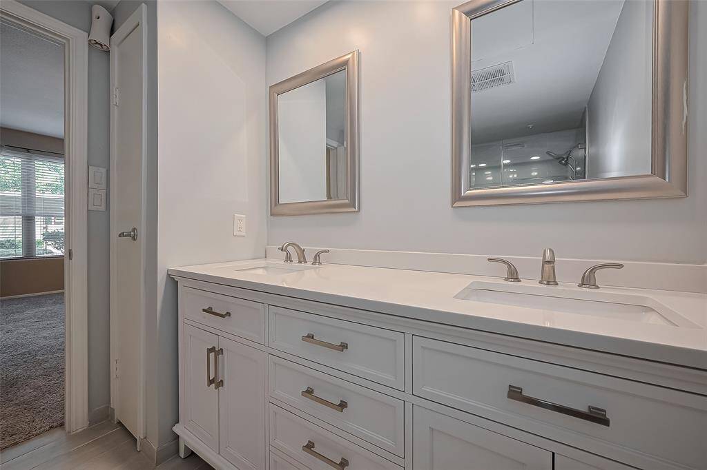 Beautifully updated primary bathroom, featuring elegant double sinks that enhance functionality and style. The modern lighting and chic mirrors add a touch of sophistication, creating a relaxing retreat that’s perfect for your daily routine.
