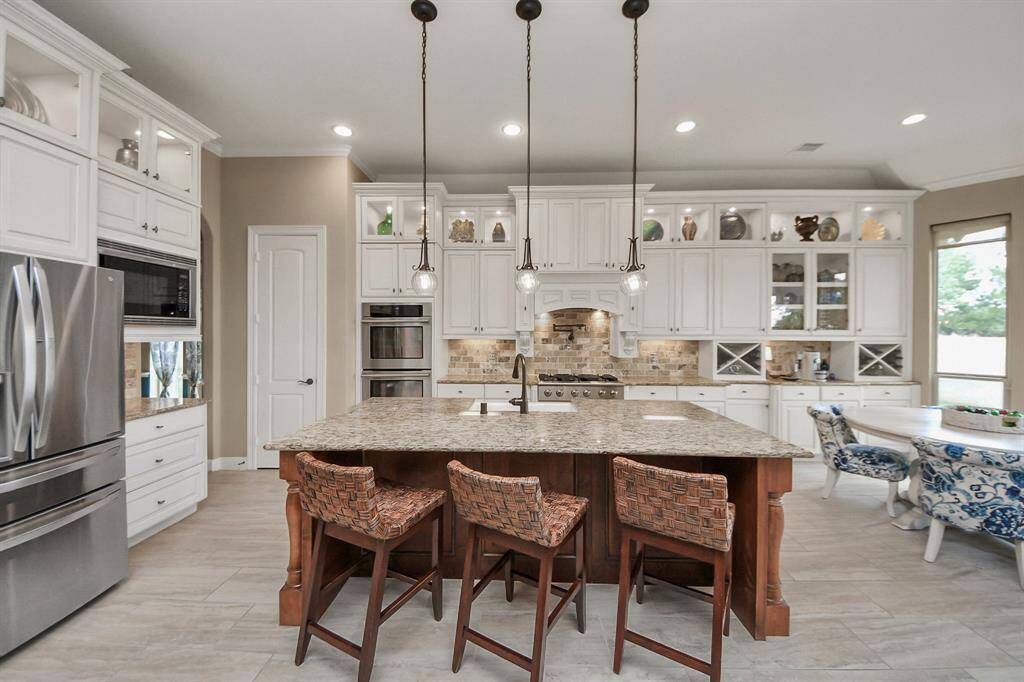 Chef’s dream island kitchen with  features custom cabinetry, all Electrolux appliances, pot filler, & flows into a designer-ceiling dining room & dramatic family room with floor-to-ceiling windows & gas fireplace.