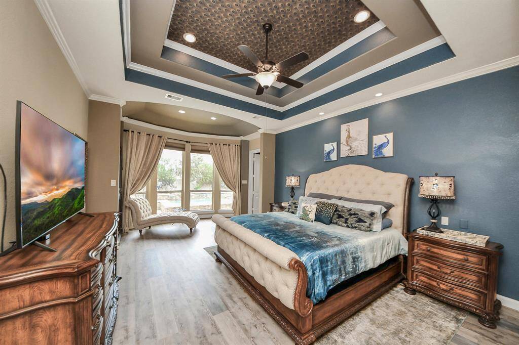 Primary Bedroom with beautiful tray ceiling and bay window overlooking the pool.