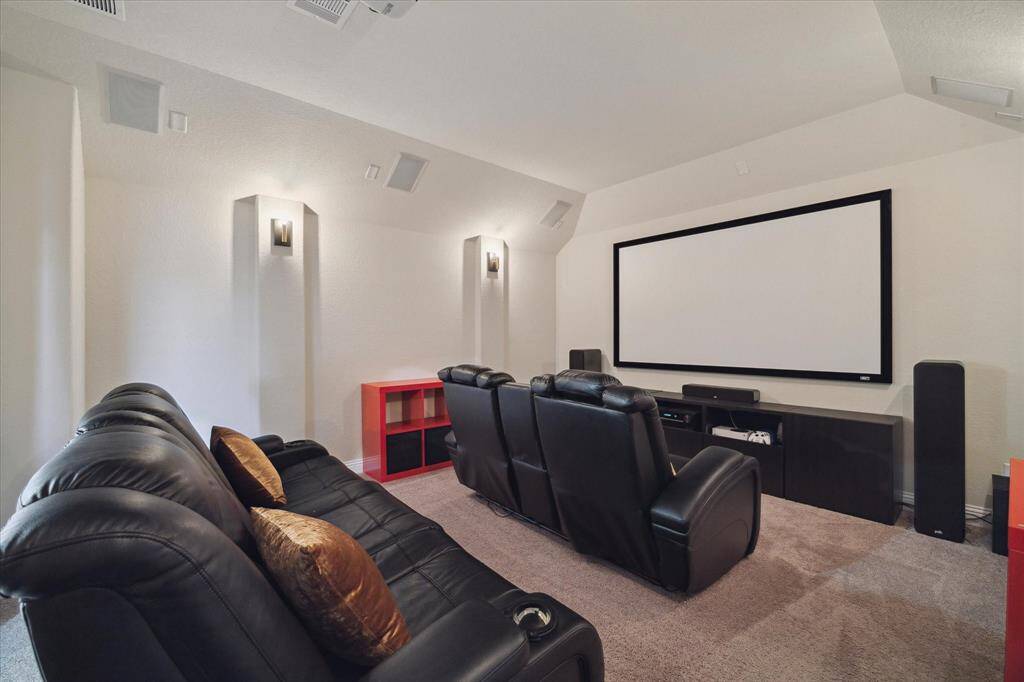 Media room with a projector, screen and surround sound system.