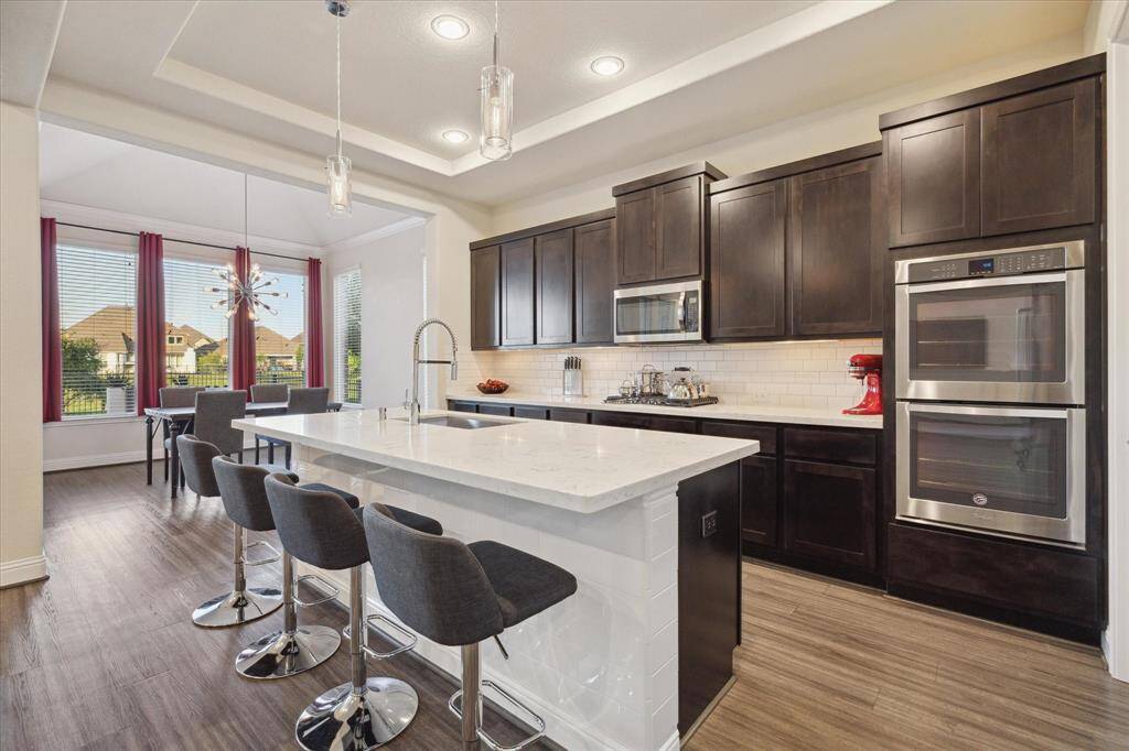 The kitchen is equipped with GE appliances, double oven, 5-burner cooktop and a KitchenAide Refrigerator.