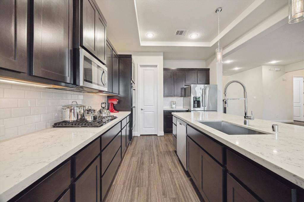 Sleek quartz countertops with a GE 5-gas burner cooktop.