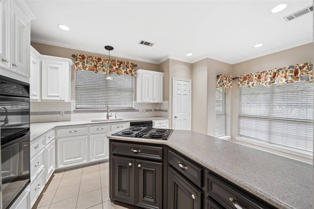 Designed for both style and function, this kitchen features durable Corian countertops with a seamlessly molded Corian sink, a Jenn-Air cooktop, oversized drawers for convenient storage, and a bar that opens to the casual dining area for easy serving and conversation.