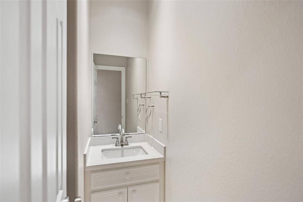 The powder bath offers added convenience for guests, complete with a single-sink vanity and a private, tucked-away location.