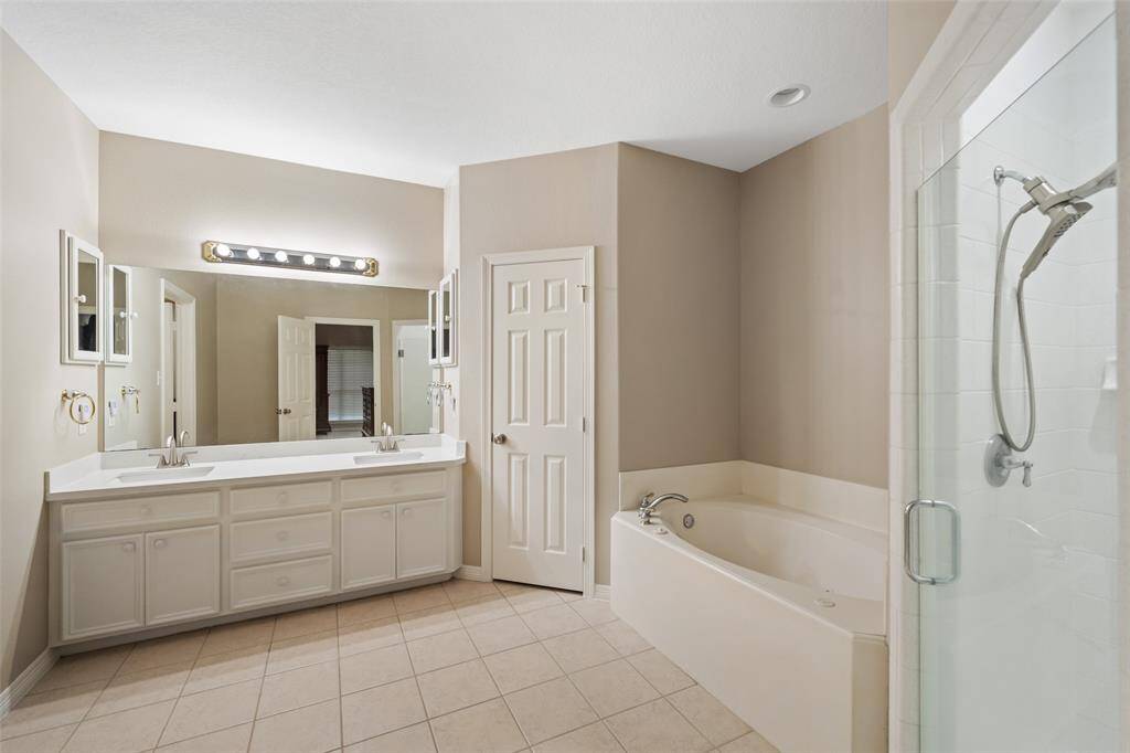 The owner’s ensuite bathroom has everything you need to start your day in comfort, including an extended dual-sink vanity with generous storage, dual medicine cabinets, and a framed mirror with vanity lighting above. Enjoy the luxury of a jetted soaking tub, a separate walk-in shower, and the privacy of a separate water closet.
