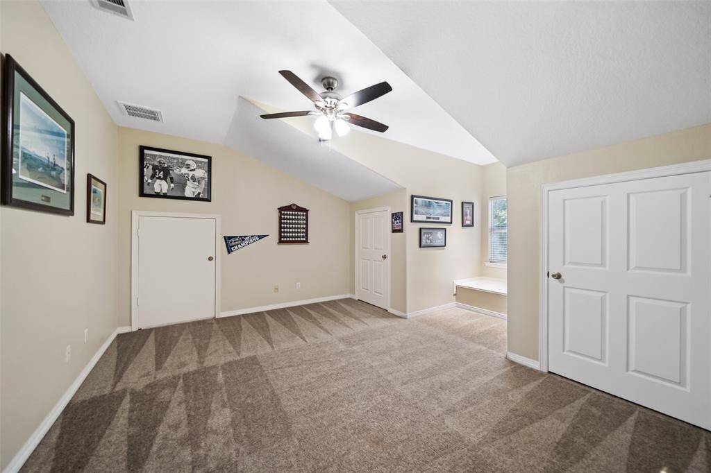 Spacious and welcoming, this upstairs suite blends comfort and charm with plush carpeting, neutral finishes, a modern ceiling fan, and a cozy dormer nook with a built-in bench, ideal for reading or relaxing. Dual closets offer ample storage, keeping the space both tidy and functional.