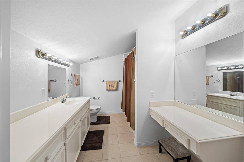 This private guest ensuite offers both comfort and convenience, featuring an extended vanity with ample storage, a separate makeup station, and a tub/shower combo ideal for daily routines or relaxing overnight stays.
