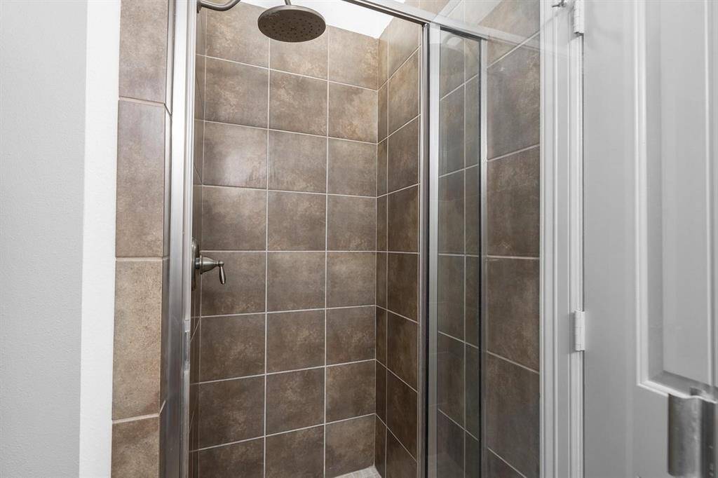 Primary bathroom separate modern shower with sleek brown tiles and a glass door, offering a clean and contemporary look.