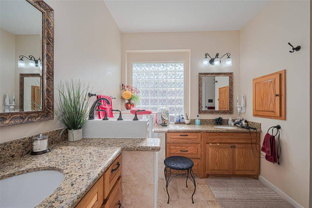 The luxurious primary bath features dual sinks, a jetted tub, and a custom walk in shower with built in seating