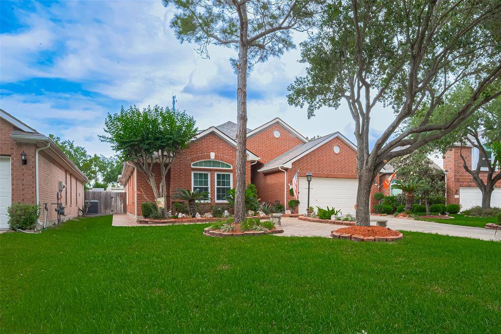 Lush greenery and vibrant blooms offer year-round curb appeal, with stamped paver walkways providing easy access