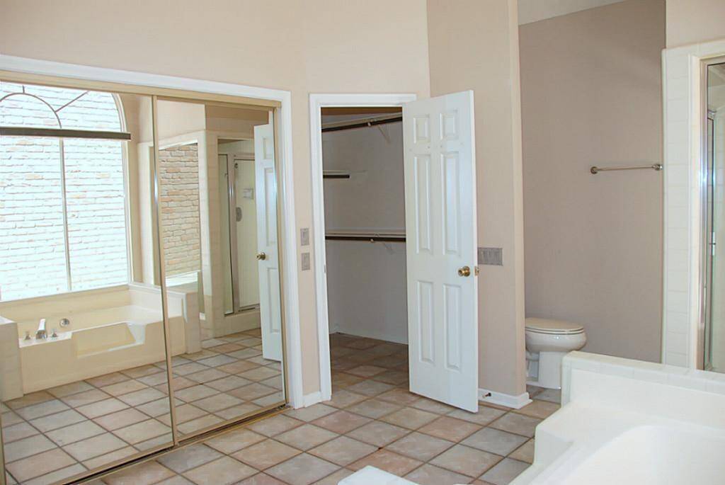Alternate view of primary bath with tile and 2 large closets.