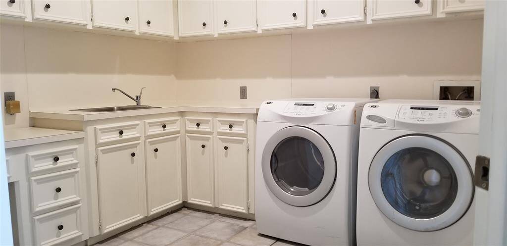 Generous sized laundry room with sink, recessed ironing board and plenty of cabinets for storage. Washer and Dryer included.