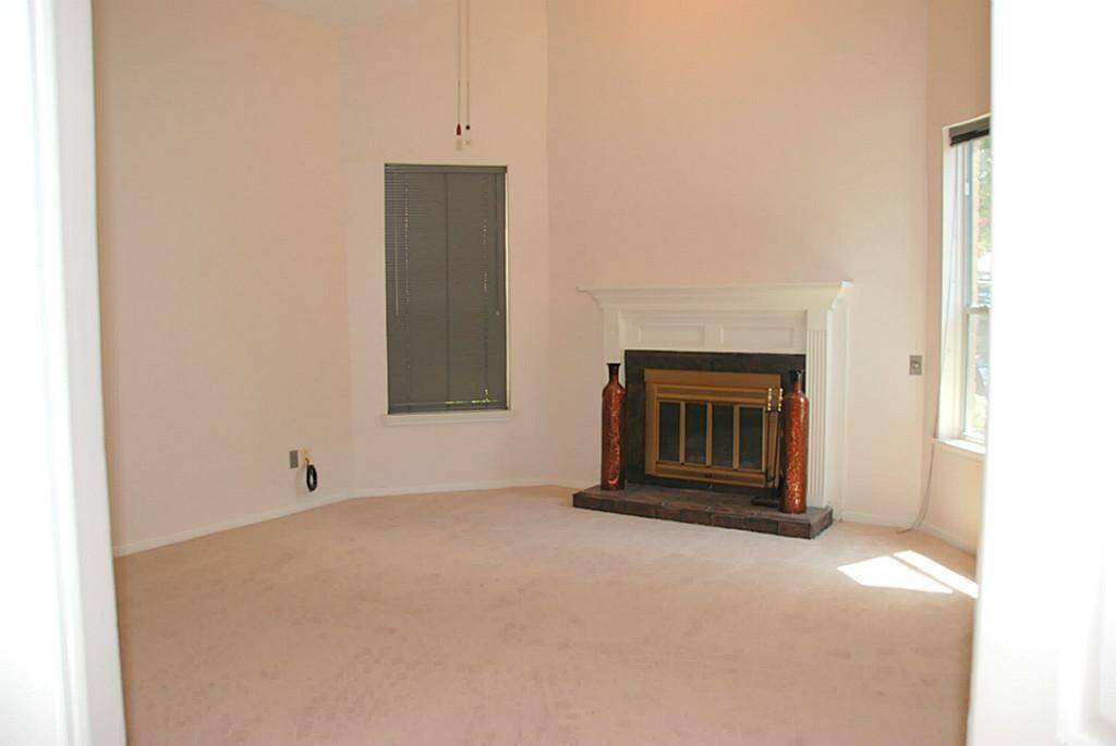 Primary bedroom with high ceilings, carpeting and wood burning fireplace.