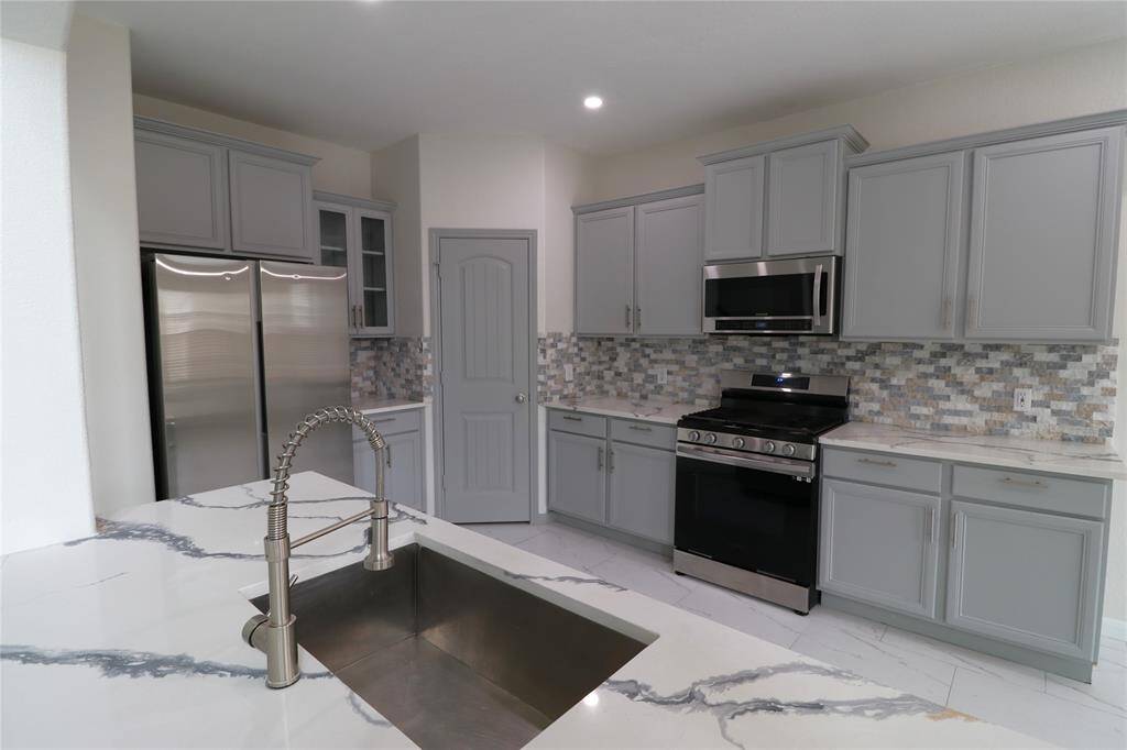 Full kitchen with quartz countertops, SS appliances and walk-in pantry.