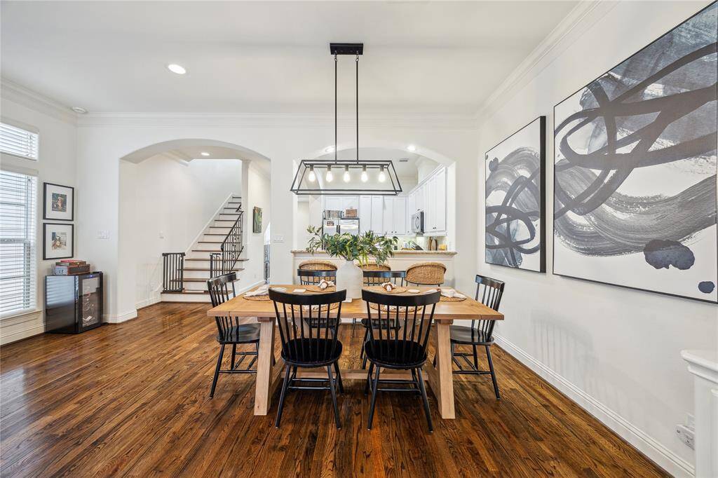 The dining room sits between the kitchen and living room. The modern chandelier anchors the space.