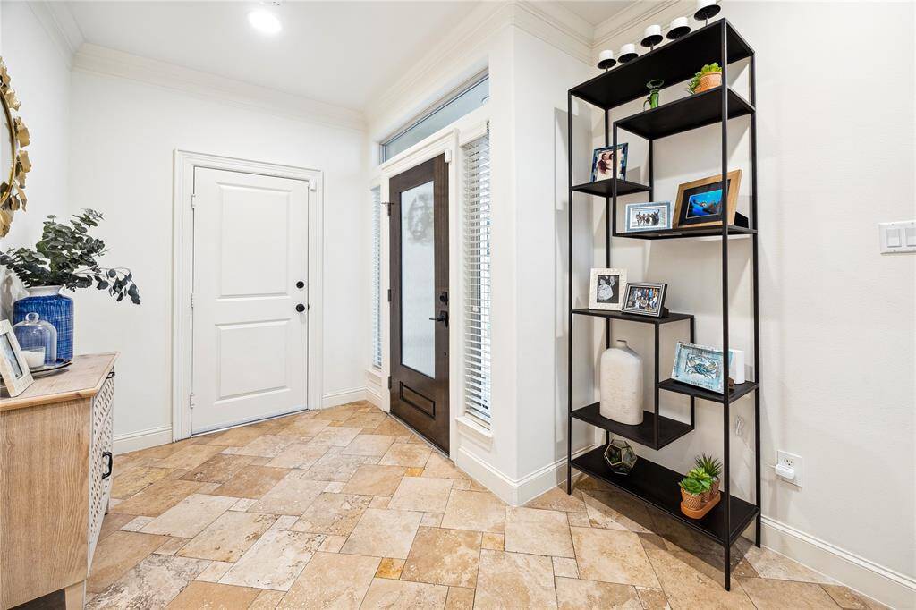 The welcoming foyer has access from the attached garage and the front door. It has travertine tile floors and a handy coat closet.