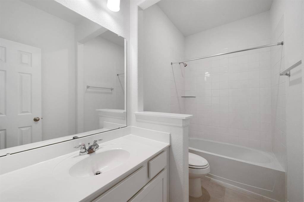The secondary bath features tile flooring, white cabinetry and light countertops and a shower/tub combo. Perfect for accommodating any visiting family and friends.