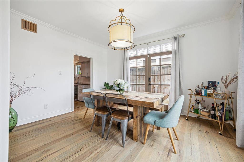 This bright dining area features hardwood floors and a modern light fixture. French doors open to a patio, enhancing the space with natural light.