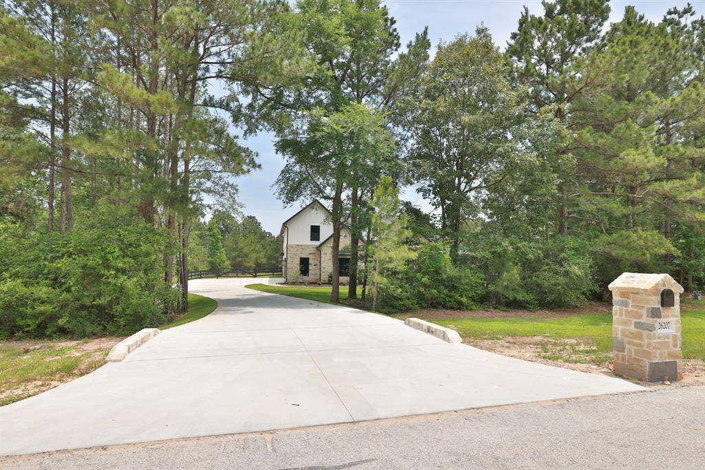 A charming stone house nestled in a wooded area with a long, driveway. The property offers privacy and a serene natural setting, ideal for a peaceful lifestyle.