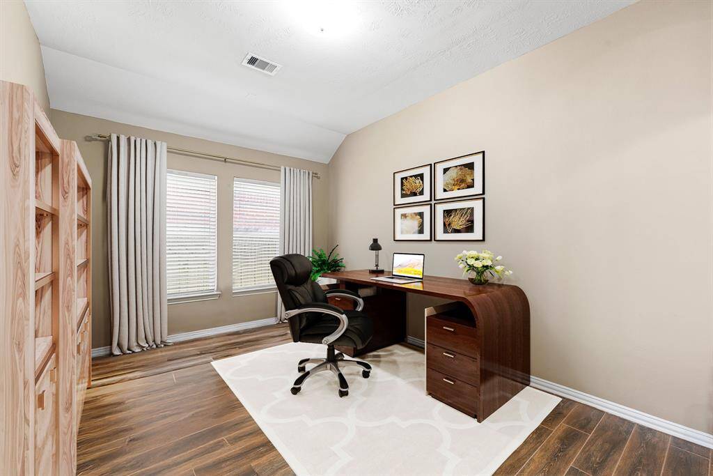 Nestled away quietly in the front of the home is the home office. Featuring high ceilings, custom paint, wood style flooring, and large windows with providing plenty of natural light. *Virtually Staged