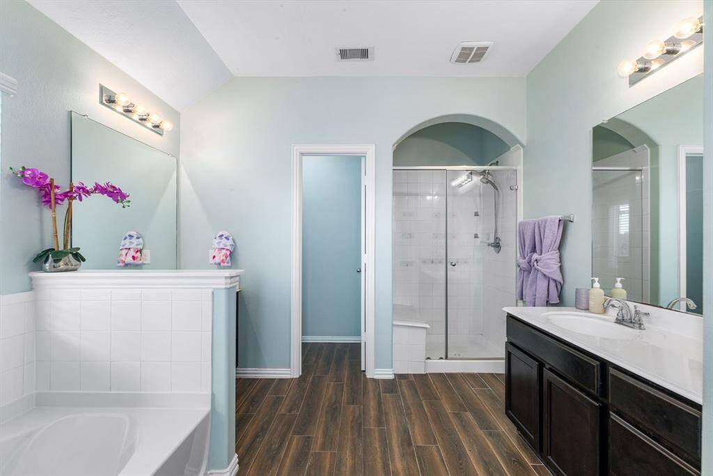 This primary bathroom is definitely move-in ready! Featuring a walk-in shower with tile surround, separate garden tub for soaking after a long day with custom tile detailing, dark stained cabinets with light countertops, spacious walk-in closet, custom paint, sleek and dark modern finishes.