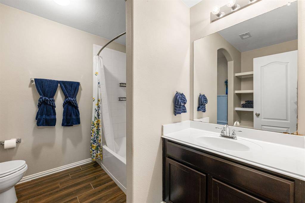 Secondary bathroom features light countertops and cabinets, custom paint, shower/tub combo with tile surround, large mirror, tile floors, sleek fixtures and modern finishes, plenty of space to accommodate any visiting family or guests.