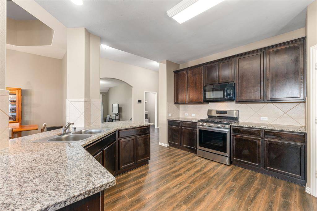 This stunning kitchen displays such a beautiful contrast with the dark stained cabinets, custom neutral paint, granite countertops, light modern backsplash, and SS appliances, recessed lighting, high ceilings and walk in pantry.