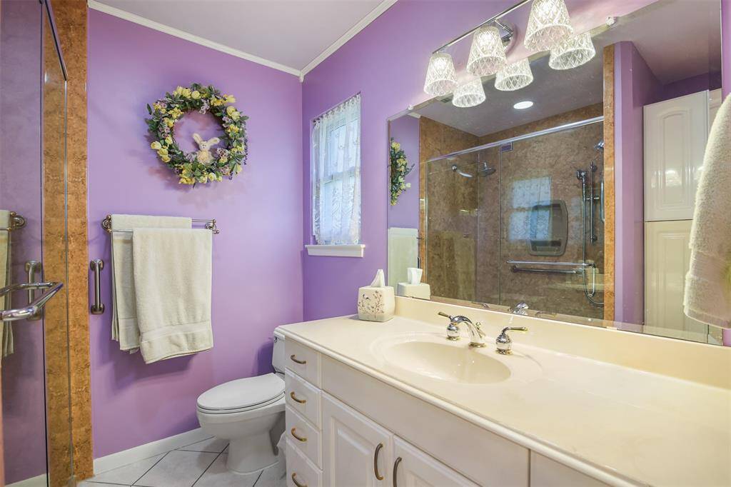 Another view of the primary bathroom with single sink vanity and tons of storage space. The glass walk in shower was remodeled in 2016.