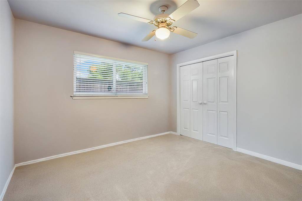 Secondary bedroom features carpet, ceiling fan closet with accordion doors.