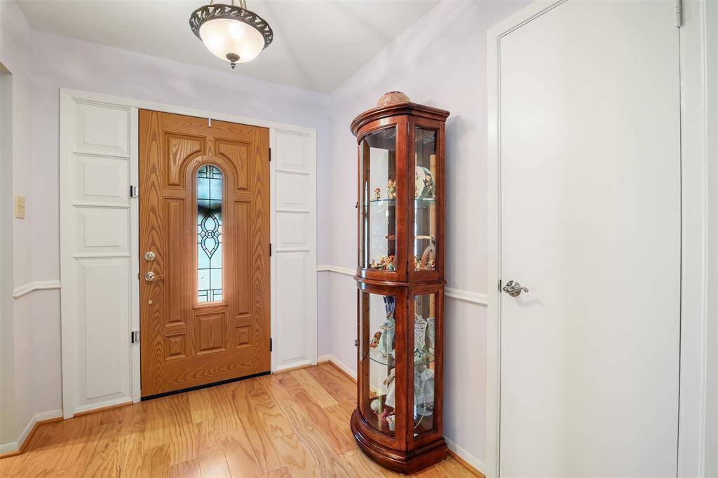 Front entry of home features engineered wood floors and front door with decorative glass detail.