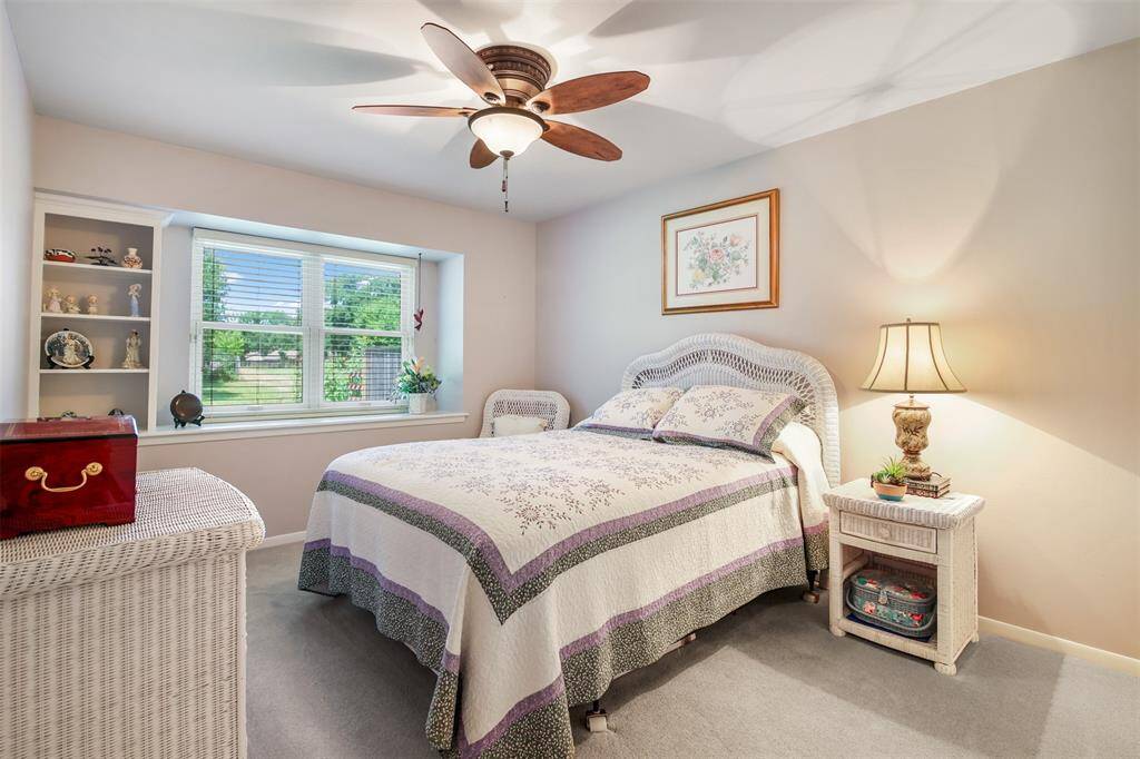 Another secondary bedroom with carpet, updated ceiling fan and picture window with built in shelving and ledge.