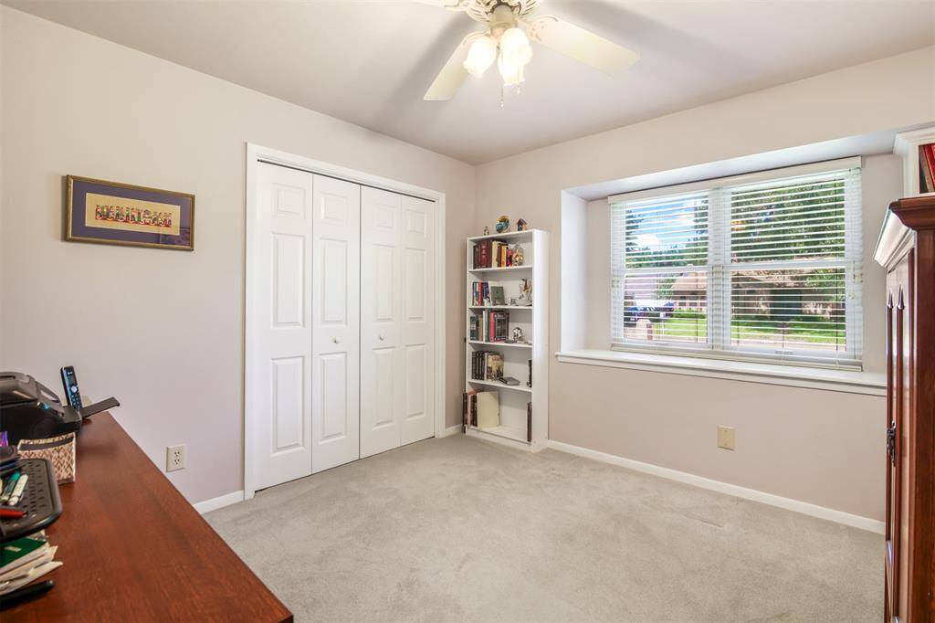 Secondary bedroom with carpet, ceiling fan and window with ledge.
