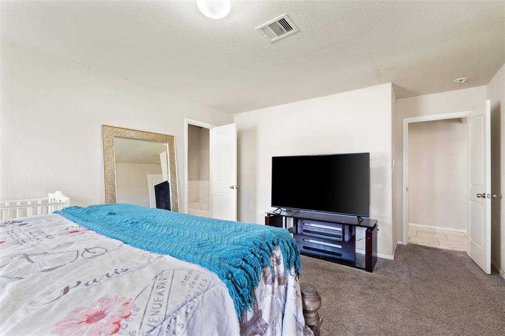 Alternate view of the primary suite showcasing easy access to the en-suite bathroom and walk-in closet. The layout provides ample wall space for large furnishings, including a media setup, and maintains a comfortable, private retreat atmosphere.