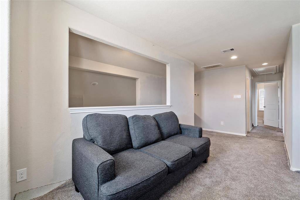 Second view of the upstairs loft showcasing a cozy sitting area with an open pass-through overlooking the living space below. This versatile area connects easily to the secondary bedrooms and full bath, offering a great setup for a playroom, media zone, or study nook.