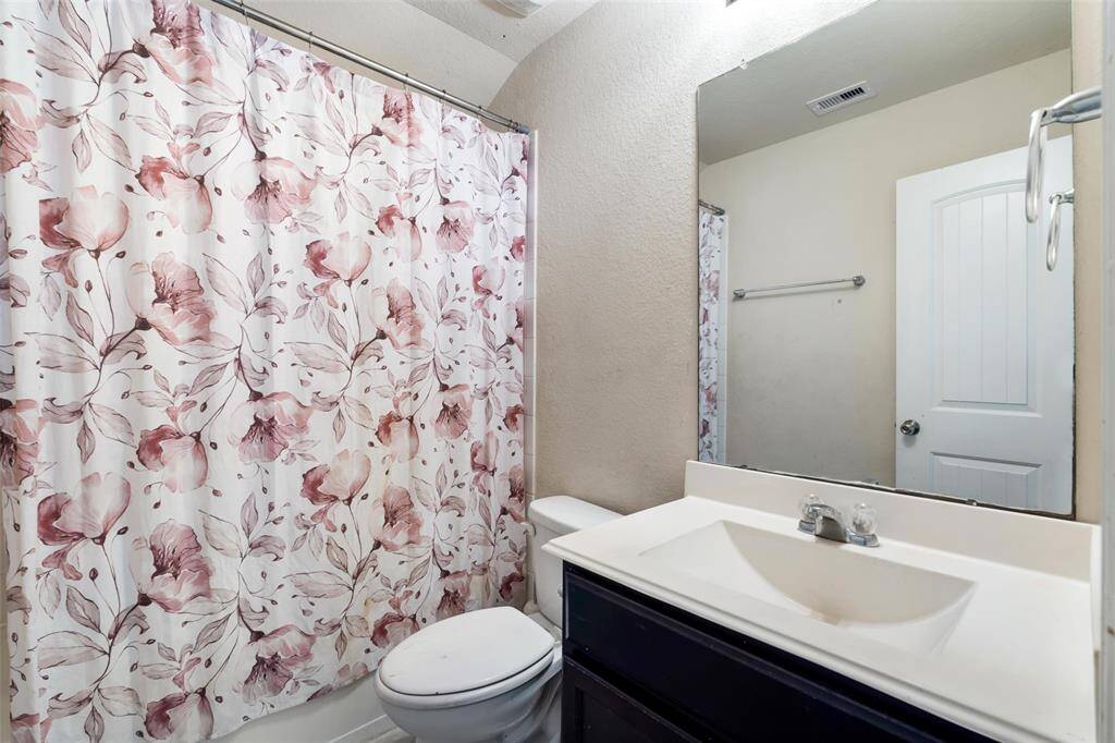 Full secondary bathroom featuring a combination tub and shower with curved arch detail, single-sink vanity, and neutral finishes. A great functional space for guests or family members.