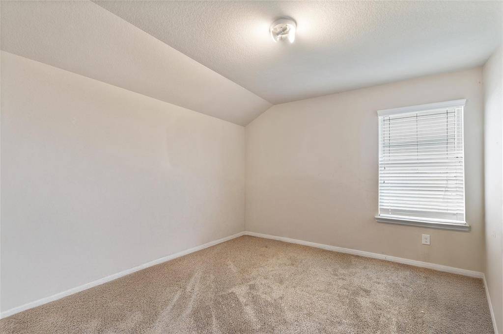 Cozy third bedroom with a vaulted ceiling, soft neutral carpeting, and natural light from a single window. A flexible space ideal for a guest room, nursery, or home office.