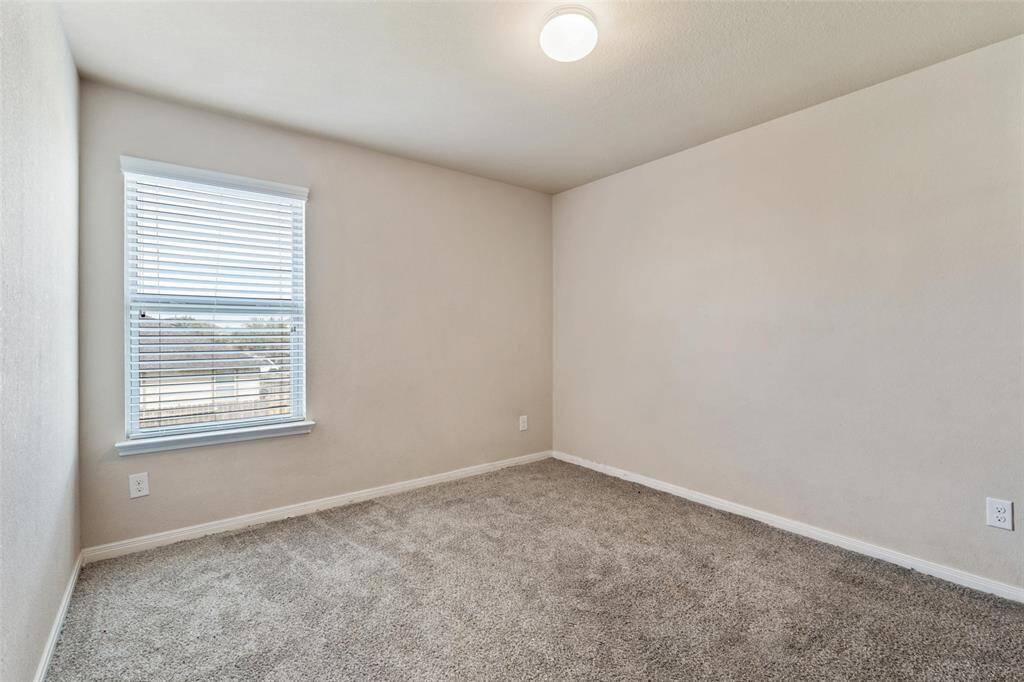 Bright fourth bedroom with soft neutral walls and a large window for natural light.