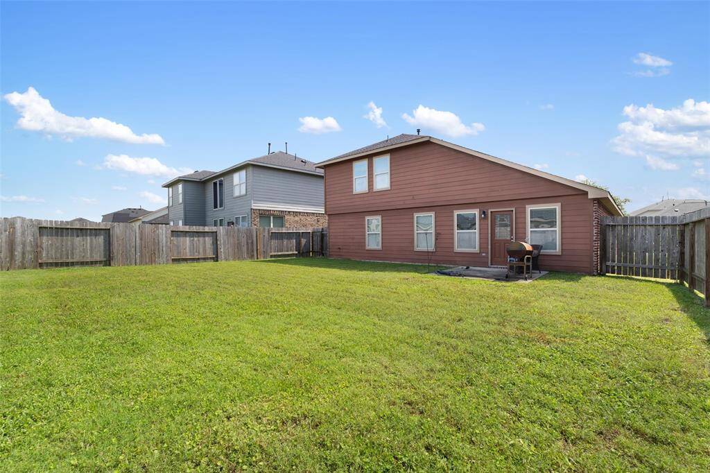 Back view of the home showcasing a large, fully fenced backyard with plenty of green space for outdoor activities and pets.