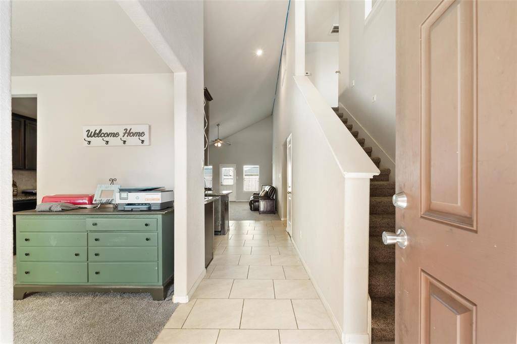 Welcoming entryway with soaring ceilings and a bright, open layout. Natural tile floor leads you into the heart of the home.