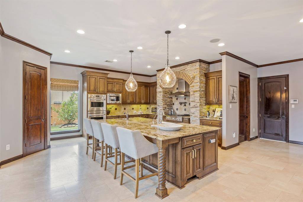 Savor the culinary delights in this Chef's kitchen, equipped with high-end appliances, elegant Granite Countertops, and rich wood cabinetry. Perfect for casual meals or gourmet creations, make every cooking experience a joyous occasion in this luxurious space!