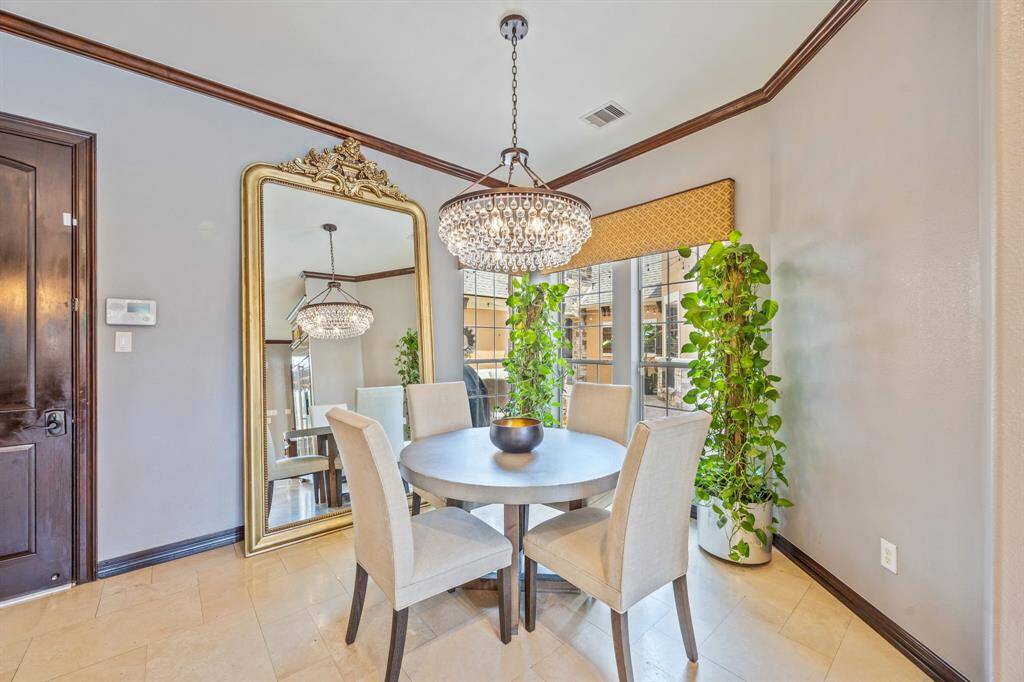 Notice the vent hood elegantly framed by a stone and brick arch, complemented by a tile backsplash featuring exquisite inserts. Thoughtfully designed pull-out drawers for pots and pans add both convenience and ease to the cooking experience.