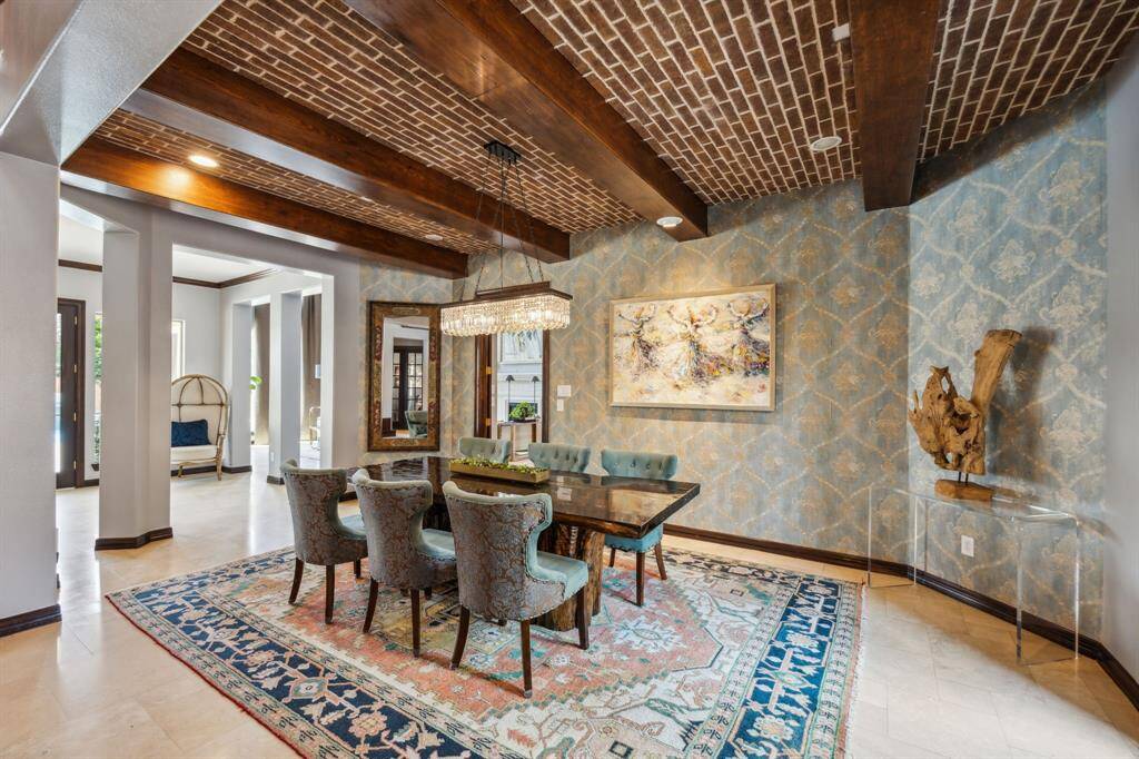 Step into elegance with this brilliant dining room, perfect for hosting unforgettable dinners or family gatherings. It features intricate millwork and a large window that fills the space with natural light. Be sure to notice the exposed ceiling beams and the beautiful wallpaper, adding a touch of sophistication to the room.