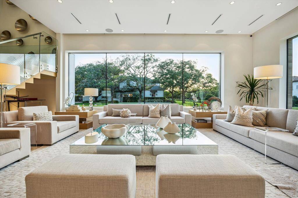 The living room showcases sleek, clean lines and is surrounded by stunning windows that flood the space with abundant natural light.