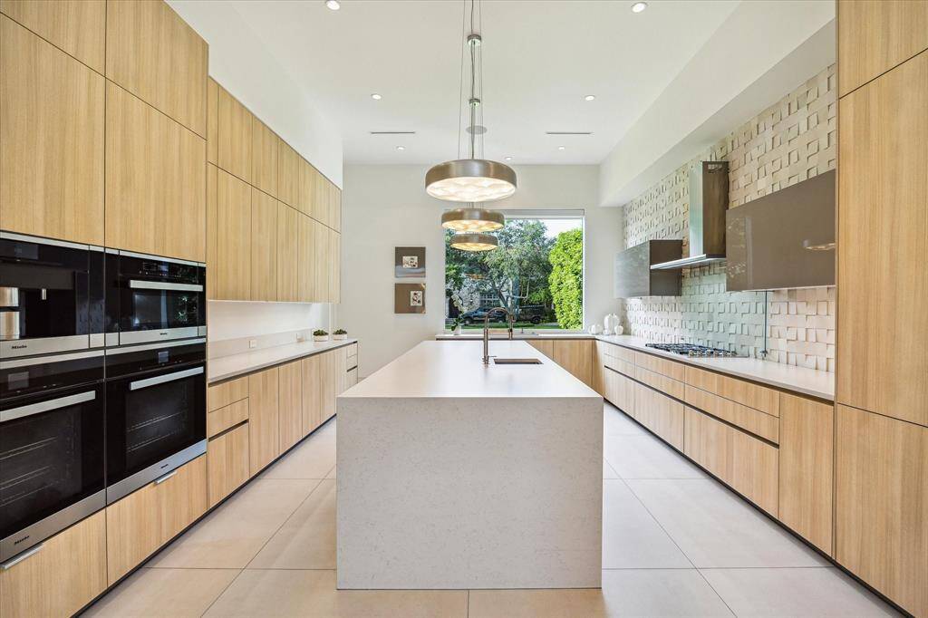 The thoughtfully designed kitchen features an oversized island and Silestone countertops with a waterfall edge, blending form and function in a truly sophisticated space.