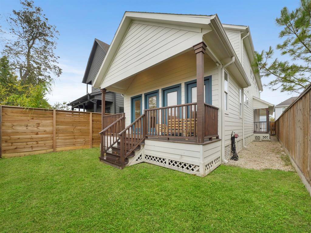 Another view of the fenced in yard with lush green space and covered porch.