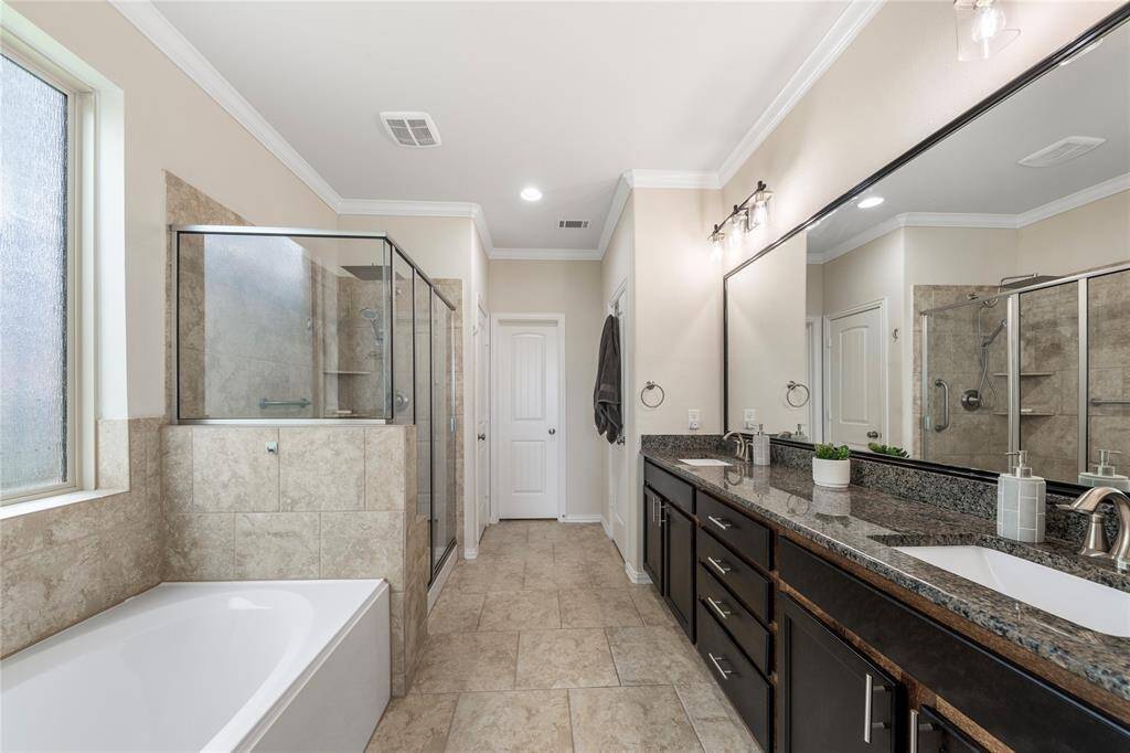 Located on the first floor, the oversized primary bedroom serves as a private retreat, featuring a luxurious en-suite bathroom with a soaking tub, dual vanities, and a separate shower.