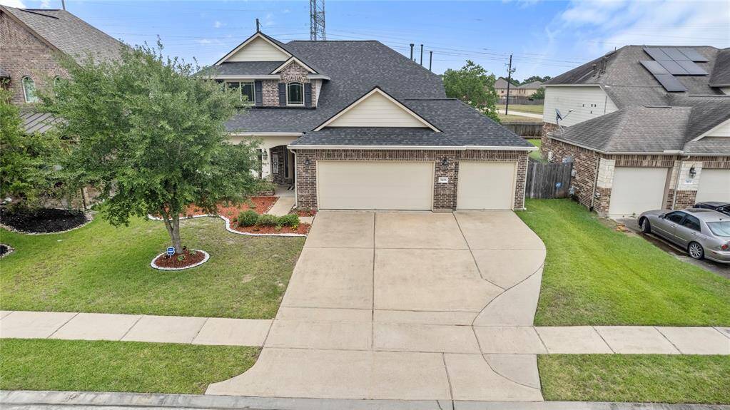 This two-story traditional home boasts a charming brick and stone façade, complemented by a well-maintained lawn and a spacious three-car attached garage.